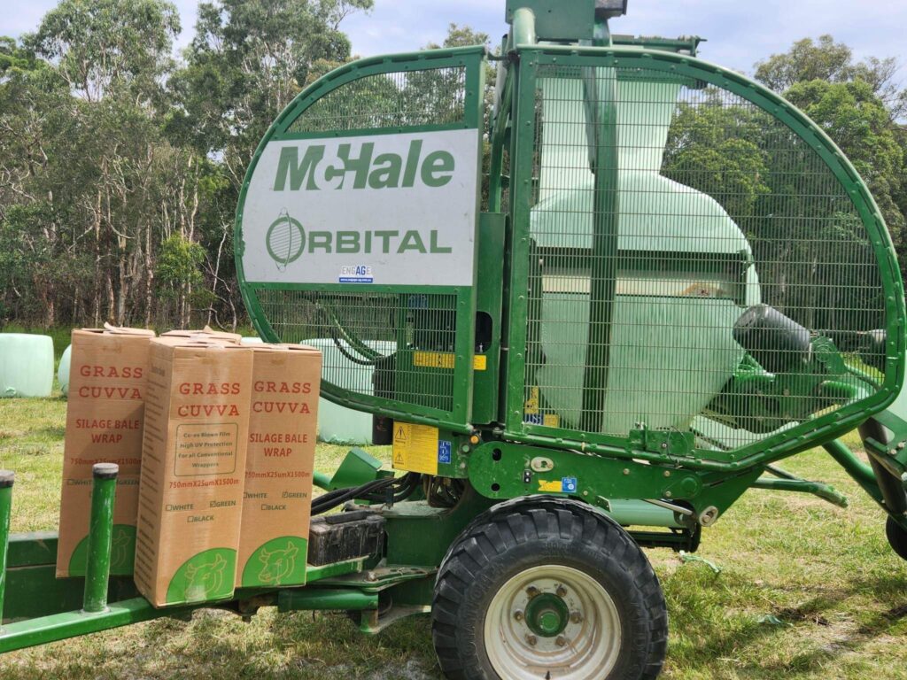 Tractor baling forage with silage wrap.