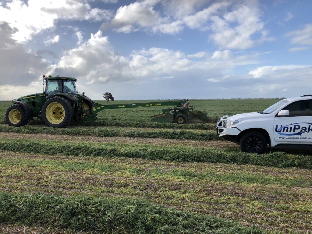 Bale being wrapped with silage film in a field.