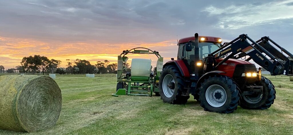 Howard baler wrapping a round bale during silage production on an agricultural field.
